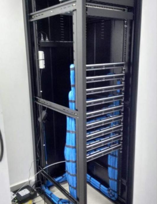 Rack aberto com cabeamento azul descendo organizadamente em bandejas — Ícaro Cabling